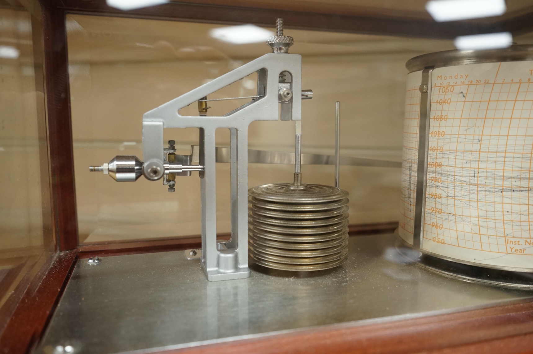 A 1970s Casella mahogany cased barograph with bevelled glass panels and a drawer underneath containing a good quantity of paper slips and instruction leaflet.
